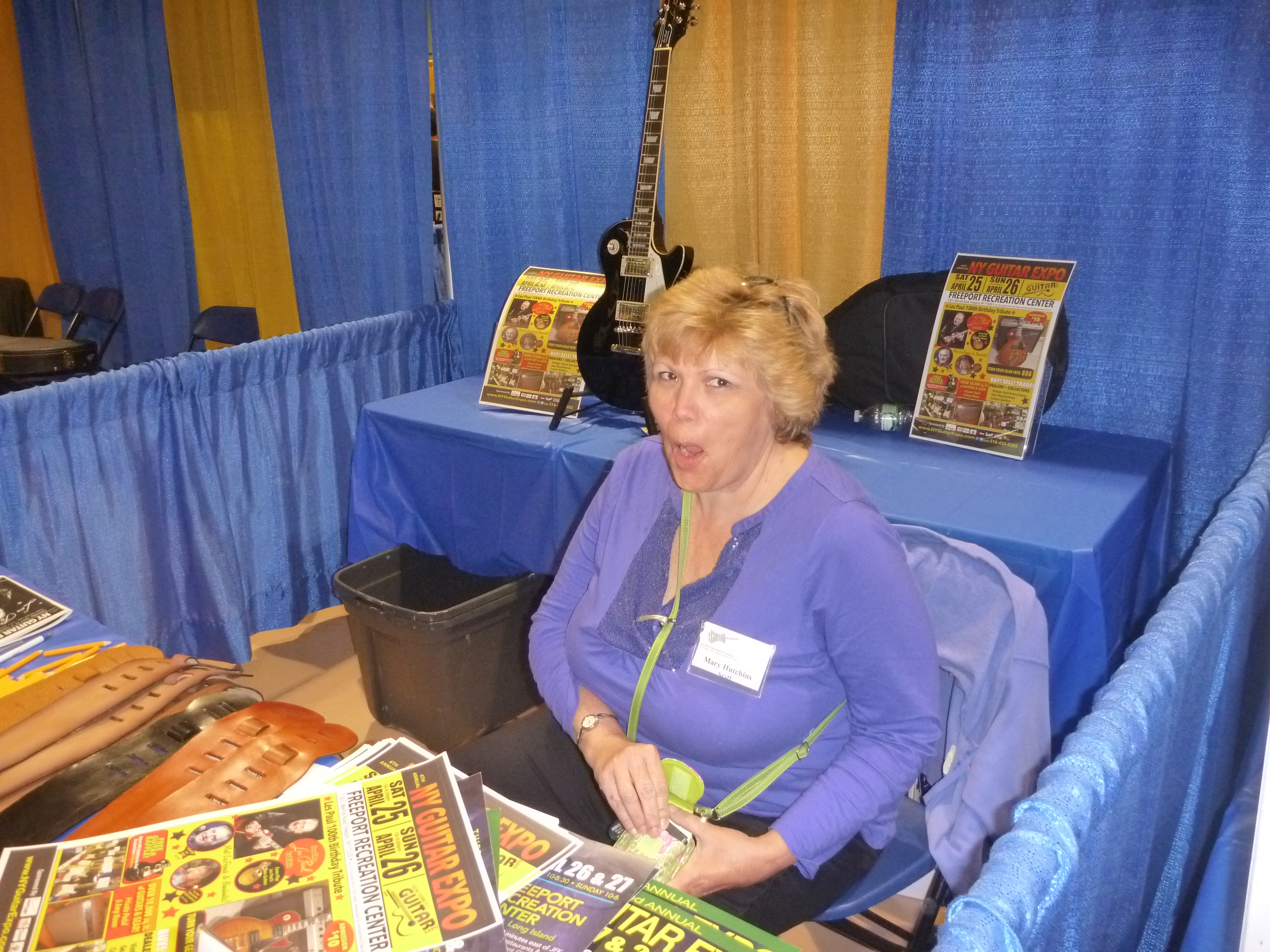 NY Guitar Show staffer Mary Hutchins surprised by the camera in the Free Guitar giveaway booth.